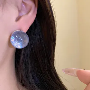 Close-up view of a translucent round purple resin stud earring worn on a model's ear
