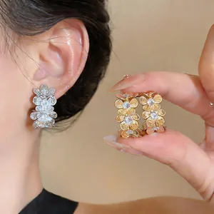 Detalle de pendientes flores de metal con circonitas en tonos plata y oro