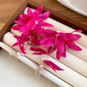 Macro view of magenta fabric flower earrings featuring pearls and crystal tassels