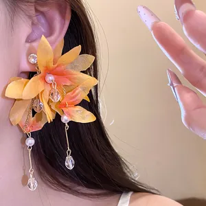 Close-up view of elegant yellow fabric flower earrings with pearls and crystal tassel detail