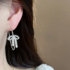 Close-up view of elegant silver bow hoop earrings with delicate white enamel details