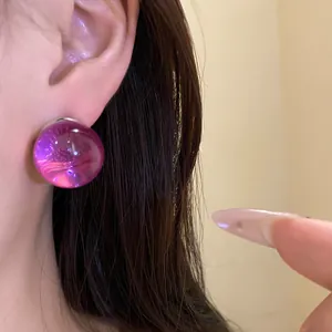 Detailed close-up of a magenta resin round stud earring worn on the ear with a silver pin