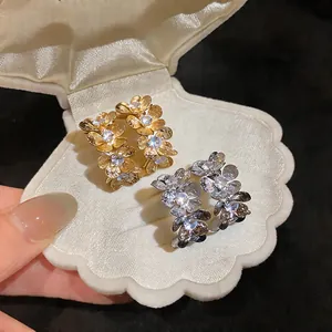Primer plano de elegantes pendientes de flores con circonitas en un joyero de concha