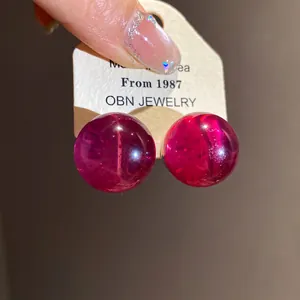 Detail view of magenta round resin stud earrings with silver needles on brand card