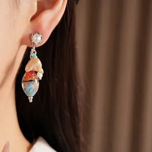 Close-up of ethnic style silver needle glass tassel earrings worn on a model ear