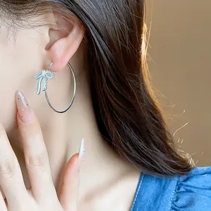Detail shot of silver hoop earring with light blue oil-drop bow-knot design