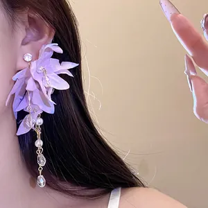 Detailed close-up of purple fabric flower tassel earrings with pearls and crystals on ear