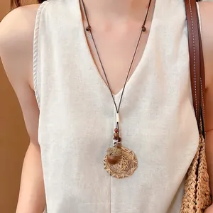 Bohemian ethnic style woven circle necklace with acorn pendant worn on a linen vest