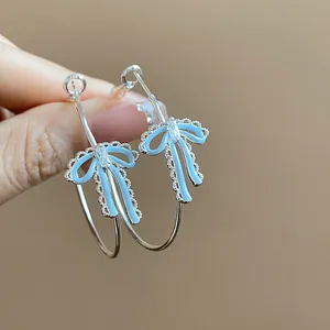 Detailed view of light blue oil-drop bow earrings with zircon accents and silver hoop