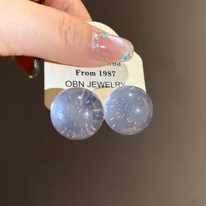 Detail view of translucent blue circular resin stud earrings held on a display card