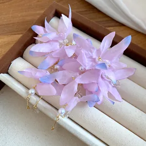 Close-up detail of pink fabric flower earrings with pearls and delicate gold tassels