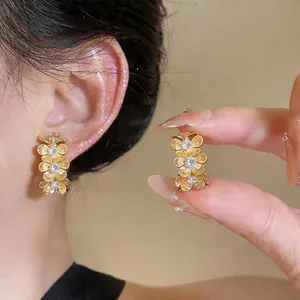 Primer plano de elegantes pendientes de flores doradas con circonitas en la oreja mujer