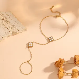 Detailed view of gold stainless steel hand chain with white flower charms on beige background