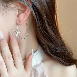 Close-up of elegant silver bowknot hoop earring worn on ear with stylish detail.