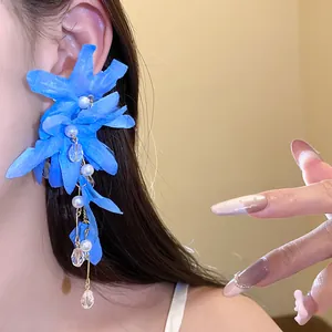 Detailed macro view of blue fabric flower earrings with pearl and crystal tassels