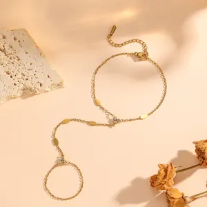 Close-up of a gold-plated stainless steel hand chain with zircon accents and oval charms.