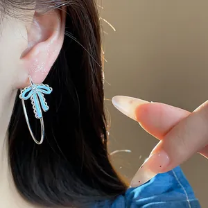 Close-up of light blue enamel bow hoop earring with cubic zirconia on model