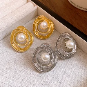 Macro detail of elegant gold and silver vintage spiral stud earrings with pearl center