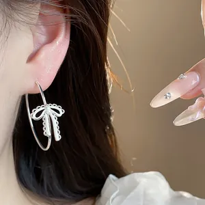 Elegant close-up view of silver bow hoop earrings with zircon and white enamel