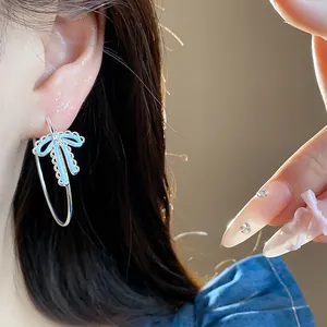 Exquisite detail of silver bowknot hoop earrings with light blue enamel and zircon