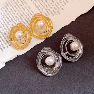 Detailed macro shot of vintage-style gold and silver swirled pearl stud earrings