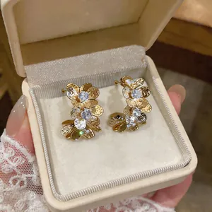 Primer plano de elegantes pendientes de flores doradas con circonitas en estuche