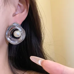 Close-up of a vintage silver entwined stud earring with pearl on ear for elegant look.