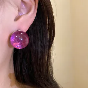 Close-up detail showing the glossy finish of a purple resin round stud earring on ear