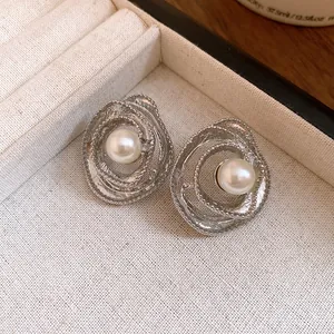 Close-up detail of vintage silver stud earrings featuring swirled circular design and pearl