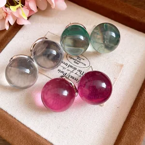 Close-up of colorful round resin stud earrings with silver needles in a jewelry tray.