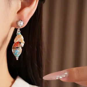 Close-up of ethnic style glass tassel earrings with intricate bead patterns and silver needle