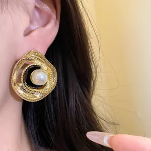 Detailed macro shot of vintage gold wrapped stud earrings featuring a central pearl