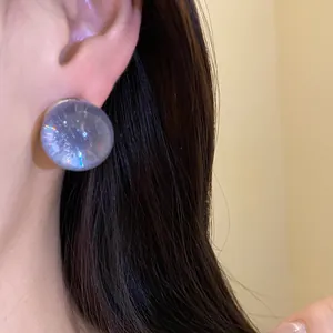 Macro detail of a minimalist round purple resin stud earring with iridescent effect