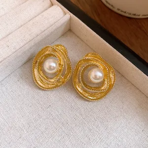 Macro detail view of vintage gold-tone textured swirl stud earrings with central white pearls