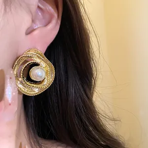Close-up of retro gold-toned circular twisted earrings with a central elegant pearl