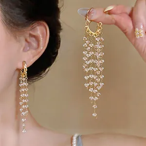 Detail view of gold tassel earrings featuring delicate dangling heart-shaped crystals.