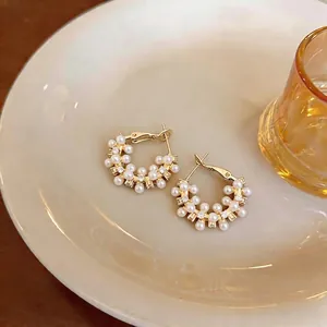 French style pearl and zircon hoop earrings with gold finish on a ceramic plate