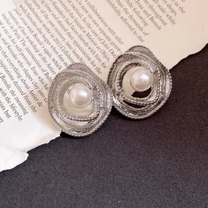 Detail view of vintage silver needle earrings with central pearl in a wrapped design.