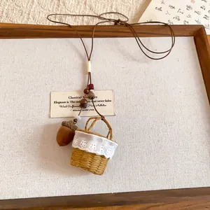 Detailed view of handmade acorn and mini woven basket charms on a rustic necklace.