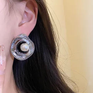 Close-up detail of vintage silver swirl stud earring with central pearl on ear.