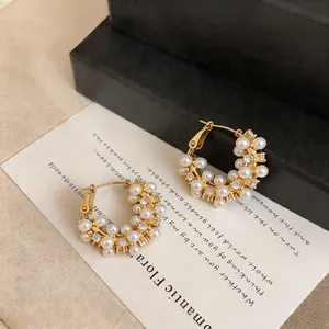 Close-up of elegant gold hoop earrings featuring pearls and sparkling zircons