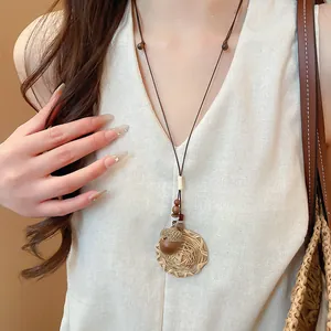 Detailed view of a New Chinese style acorn pendant necklace worn on a linen outfit