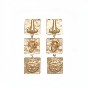 Gold square ear studs featuring unique surrealist facial feature reliefs for women