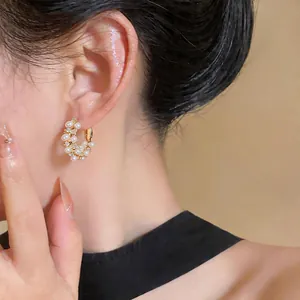 Close-up of elegant gold hoop earrings with pearls and zircons on model's ear