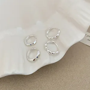 Macro view of silver lace earrings and blue zircon hoops on ceramic tray