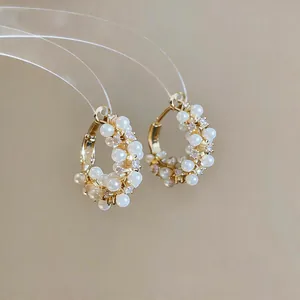 Close-up of elegant gold hoop earrings with small pearls and shiny zirconia stones