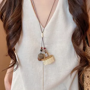 Detail of handcrafted acorn and tiny woven basket pendants on a long cord necklace