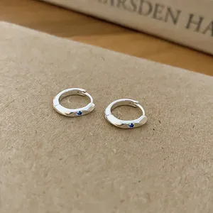 Detailed close-up view of elegant silver hoop earrings with a blue zircon stone inlay
