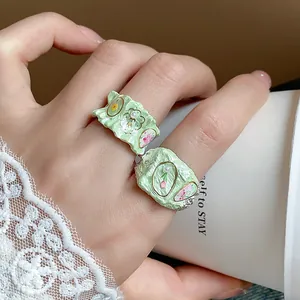 Gros plan détaillé de bagues vert clair émaillées avec motifs floraux et perles