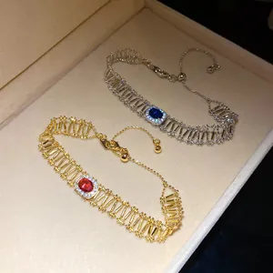 Detailed view of vintage-style hollow bracelets with oval red and blue zircons in a box.